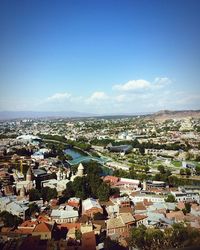 High angle view of houses in town against blue sky