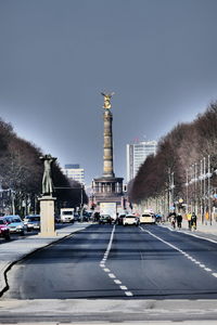 Victory column on street in city against cloudy sky