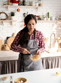 Young woman preparing food on table at home