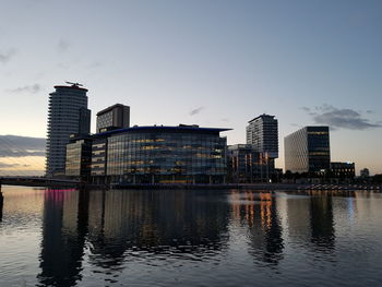Buildings by river against sky in city