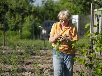 Woman holding plants on field