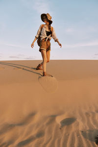 Full length of woman standing at sandy beach