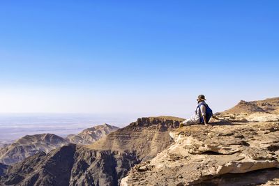 Woman standing on cliff against clear sky