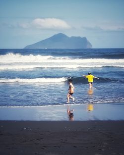 Full length of man and woman at beach against sky