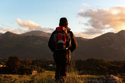 Rear view of man standing on mountain against sky