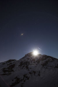 Low angle view of snowcapped mountain against sky at night