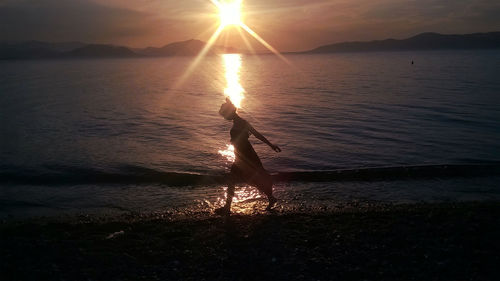 Silhouette man on beach against sky during sunset