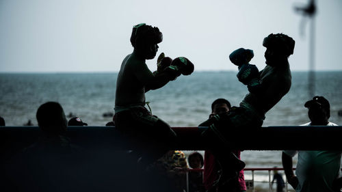 People at sea against sky