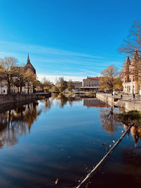 Building by river against blue sky