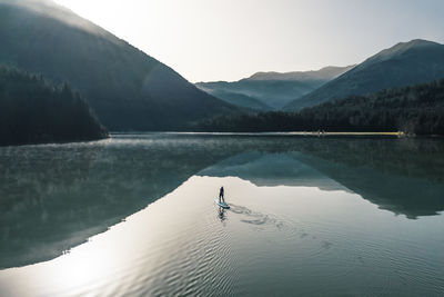 Woman paddleboarding on sylvenstein lake, bad tolz, bavaria, germany