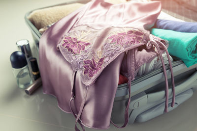 Close-up of pink nightie in suitcase on tiled floor
