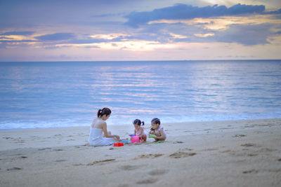 People on beach against sky during sunset