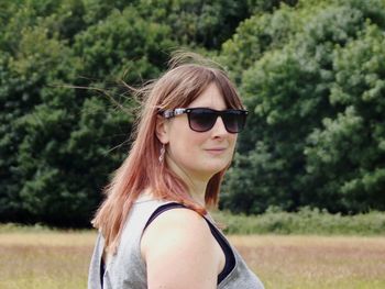 Side view portrait of woman wearing sunglasses on field