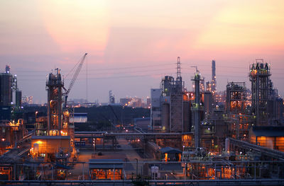 Illuminated factory against sky during sunset