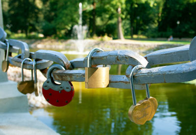 Symbolic love padlocks fixed to the railings of a bridge with a fountain in a park on background
