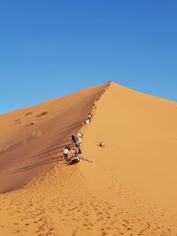 Scenic view of people on desert against clear sky