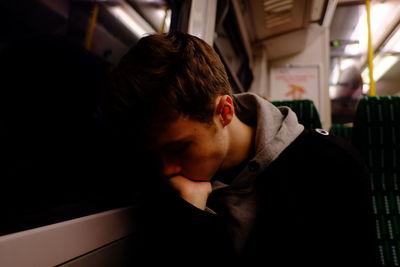 Man with hand on chin sitting by window while traveling in train