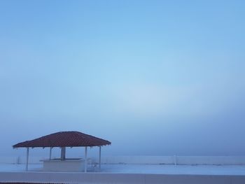 Lifeguard hut on snow covered roof against clear blue sky