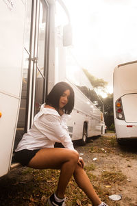 Side view of young woman sitting on car window