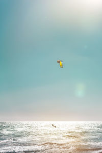 Person paragliding in sea against clear sky