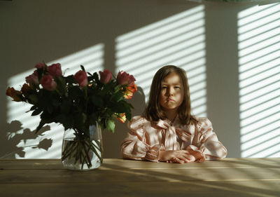 Portrait of girl sitting on table at home