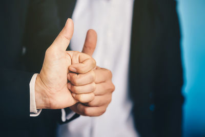 Midsection of businessmen showing thumbs up sign