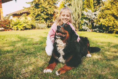 Smiling girl sitting with dog at lawn