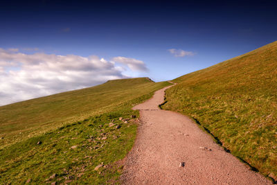 Road leading towards mountains against sky