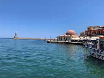 Scenic view of sea and buildings against clear blue sky