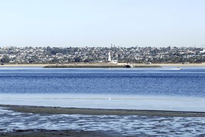 Sea by cityscape against clear sky