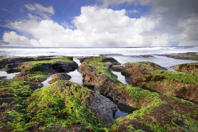 View of rocky beach against cloudy sky