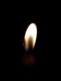 Close-up of lit candle in darkroom