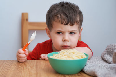 Cute boy is playing with his pasta at lunch time