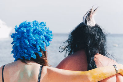 Rear view of young women wearing headdress against sea