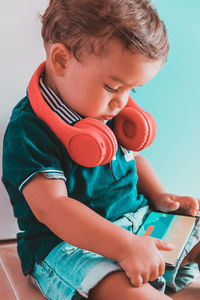 Cute boy looking away while sitting on mobile phone