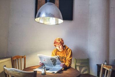 Woman reading newspaper at table