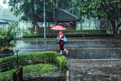 Full length of man holding umbrella during rainy season