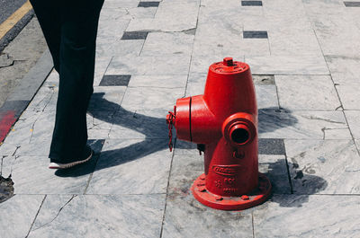 Low section of person walking by fire hydrant on footpath