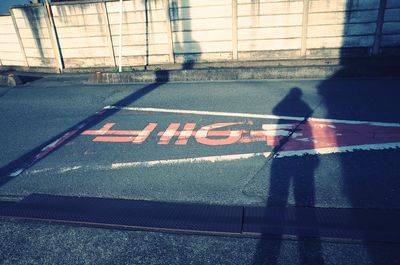 Shadow of man walking on road in city