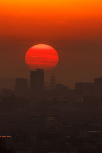 Silhouette of water tower against orange sky