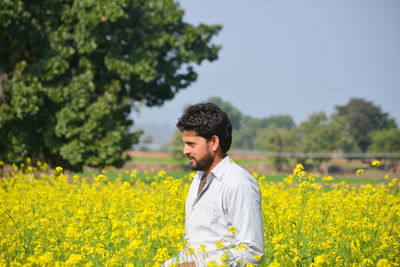 Young indian farmer at black mustard field