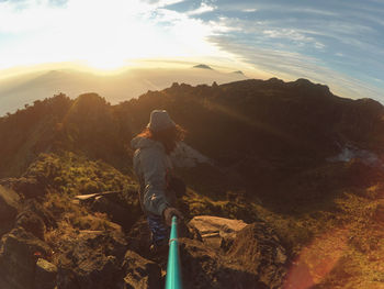 Rear view of man walking on mountain against sky