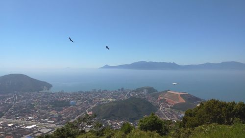 Aerial view of townscape by sea against sky