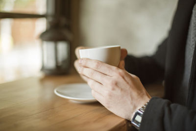 Midsection of man holding coffee cup