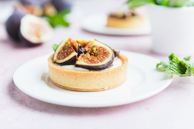 Tartlets pastry with white cream, topped with figs and pistachio. cooking concept. healthy dessert.