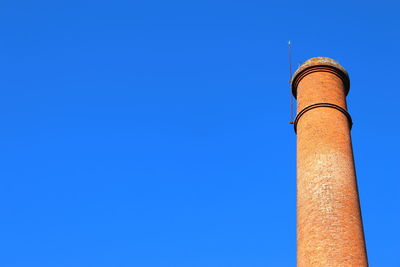 Low angle view of brick chimney against clear blue sky