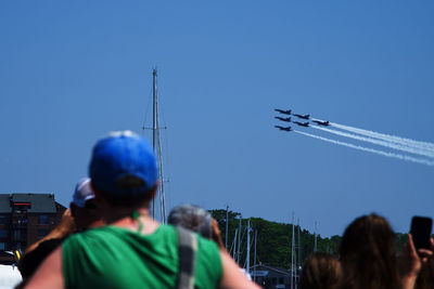 Rear view of people at airplane against clear blue sky