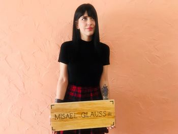 Portrait of young woman standing against wall