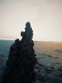 Statue on beach against clear sky