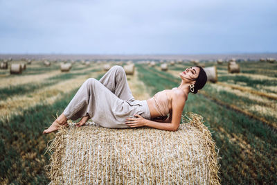 Woman relaxing on field against sky